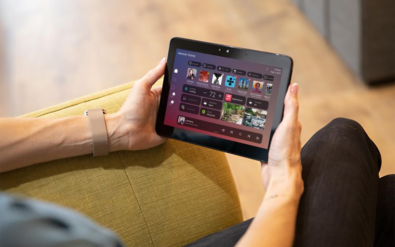Hands holding a tablet showing a smart home control app