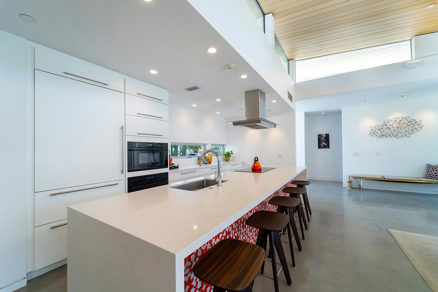 Modern bright kitchen with white cabinetry and island seating under skylights