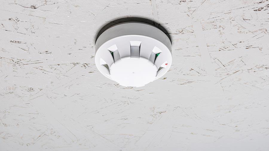 White smoke detector mounted on a textured ceiling
