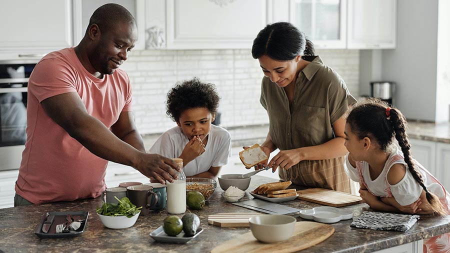 Family of four preparing food together in a bright modern kitchen