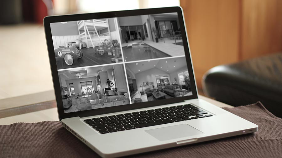 Laptop displaying four live security camera feeds of a home interior and pool area