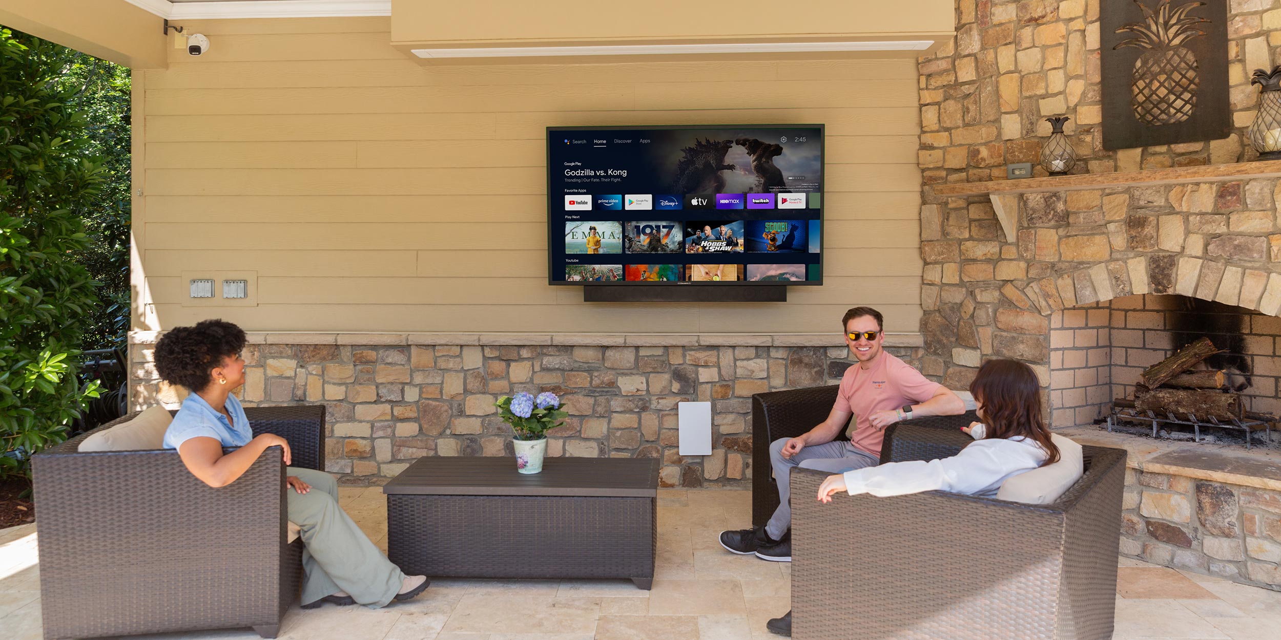 People sitting on a patio watching a wall-mounted television