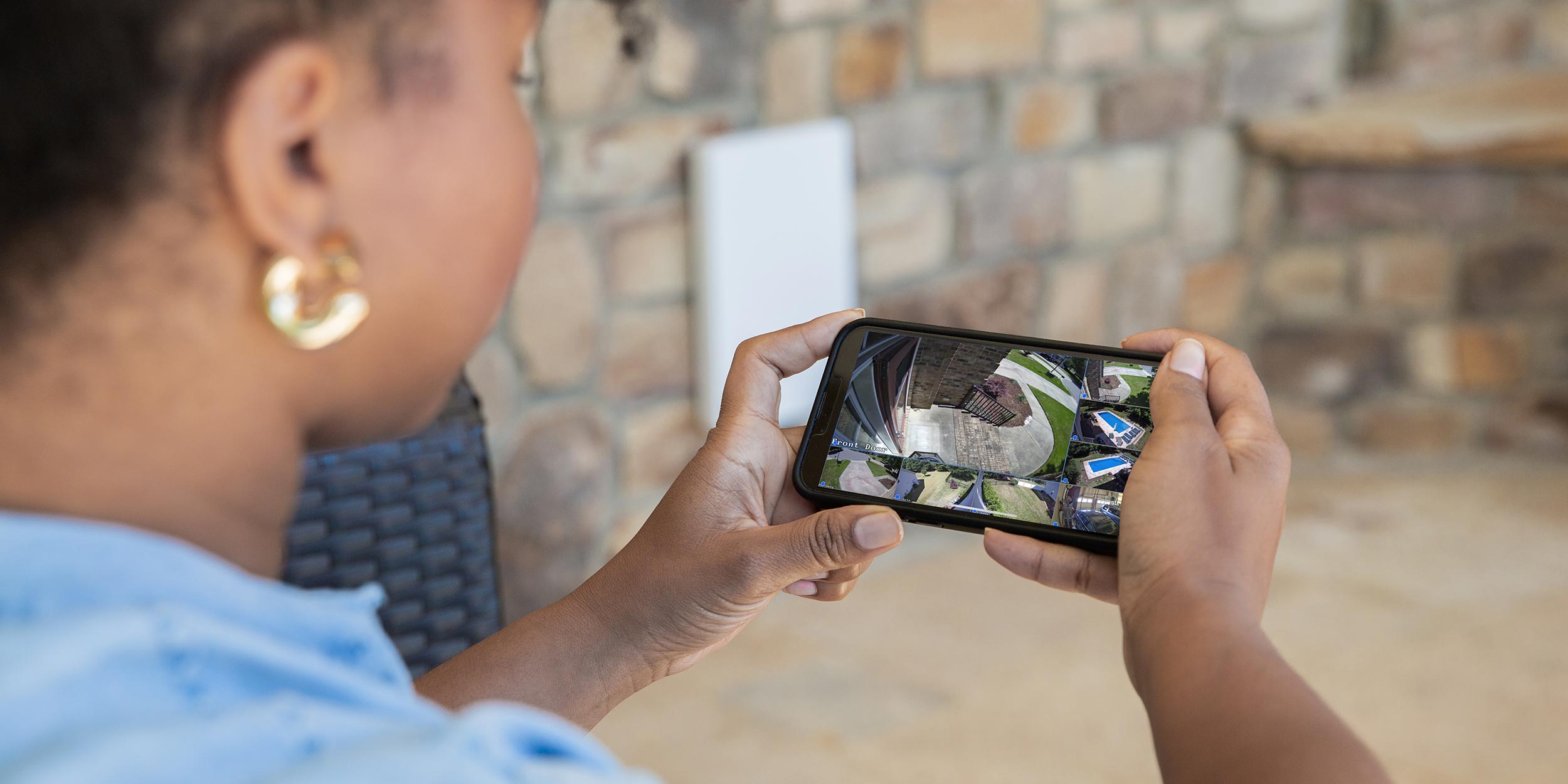 Close-up of a person viewing multiple security camera feeds on a phone