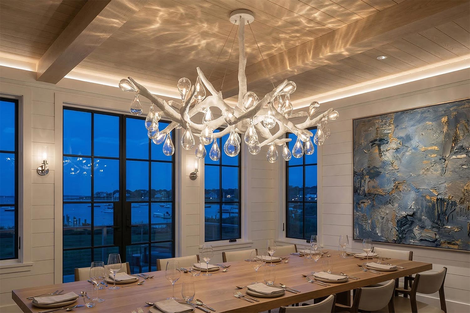 Sculptural white branch chandelier with glass droplets over a long wooden dining table