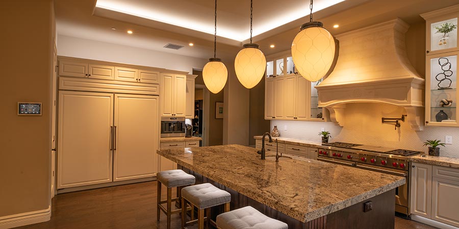 Luxury kitchen with a large granite island, pendant lights, and integrated appliances