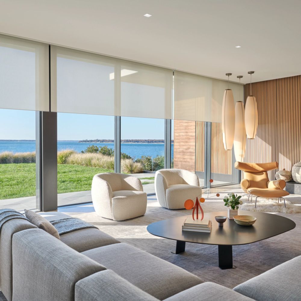 <span class="uk-h4">A modern, sunlit living room featuring floor-to-ceiling windows with a lake view and automated roller shades.</span>