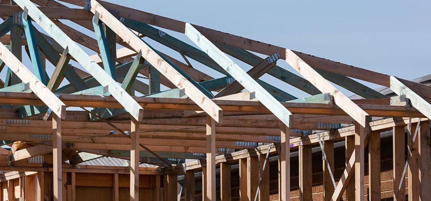 Wooden framing of a new residential building under clear blue sky